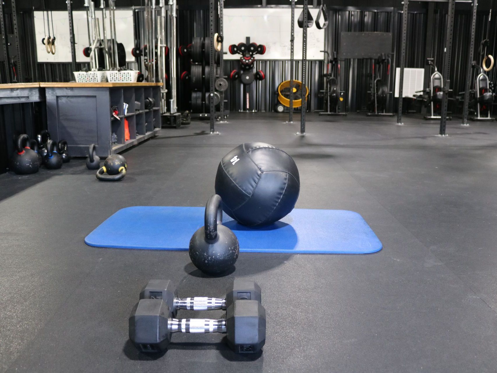 A man is helping another man lift a dumbbell in a gym.