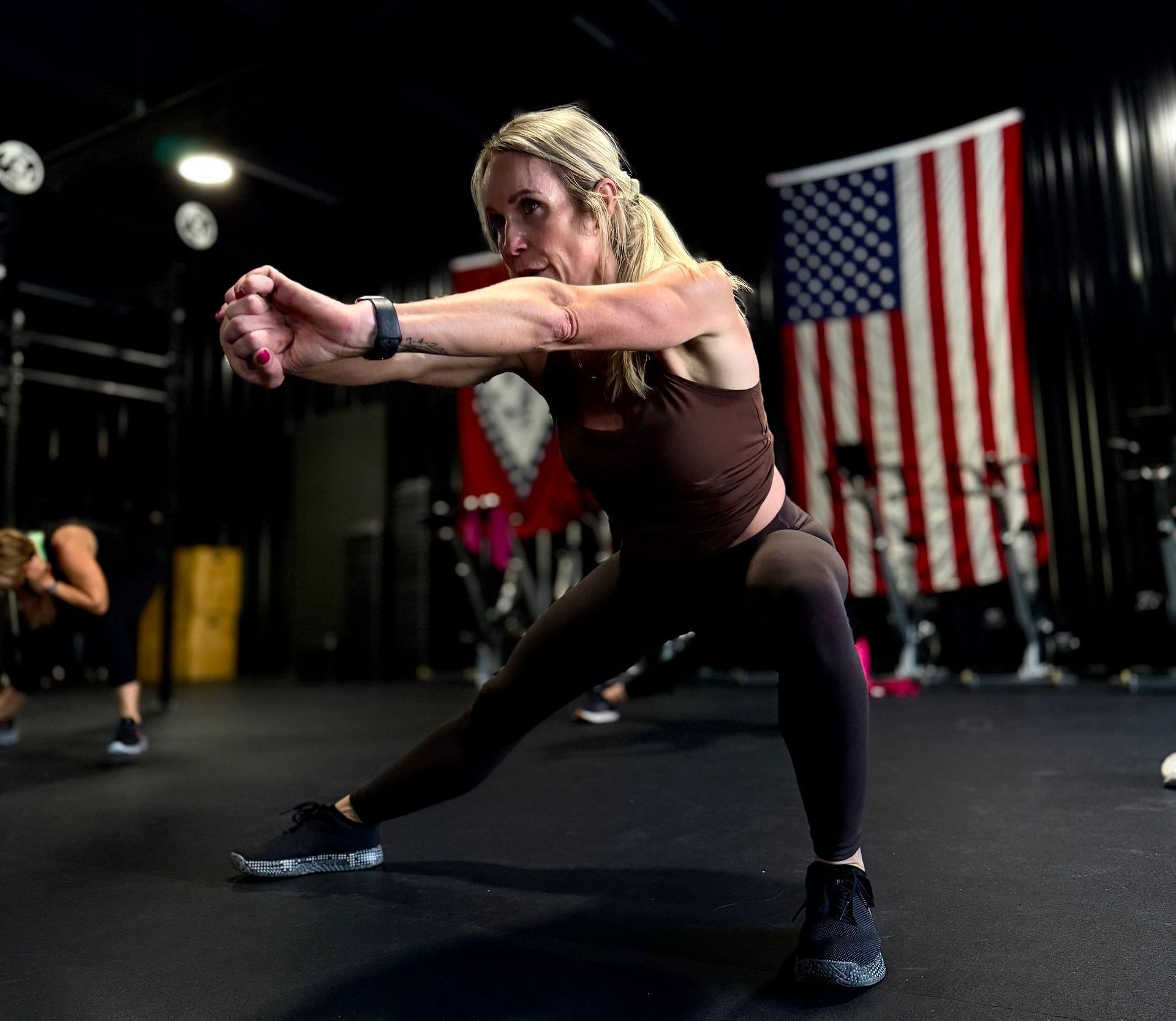 A woman is stretching her legs in a gym