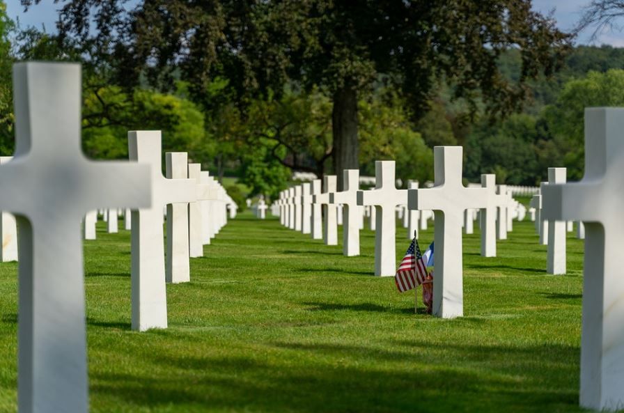 A cemetery filled with lots of white crosses and american flags.