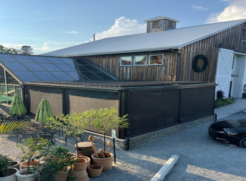 A large wooden building with a lot of potted plants in front of it.