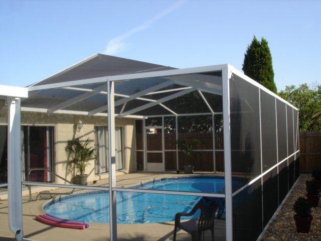 Pool enclosed by a white screened structure. Pool is blue, and the sky is clear.