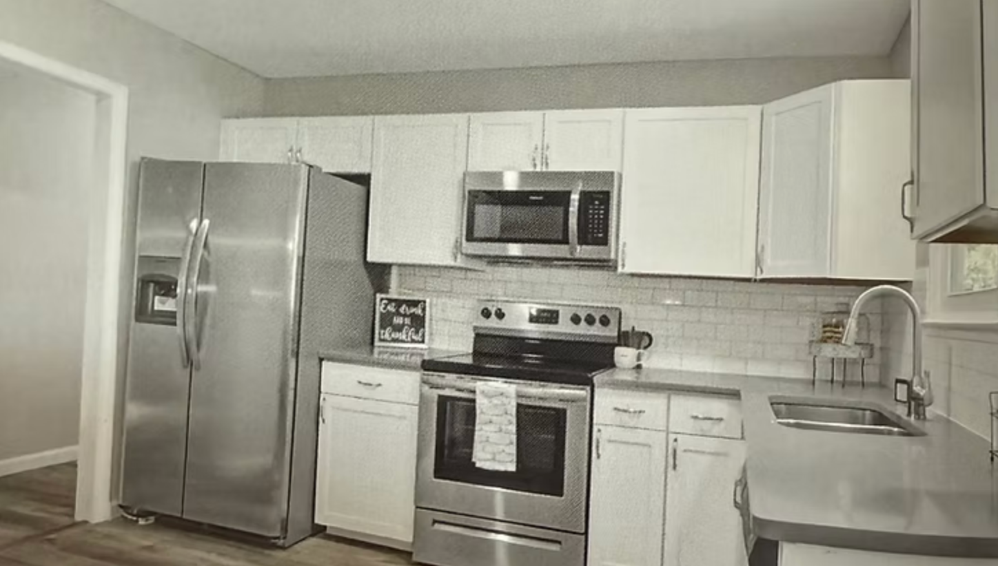 Stainless steel kitchen appliances, white cabinets, and a gray countertop.