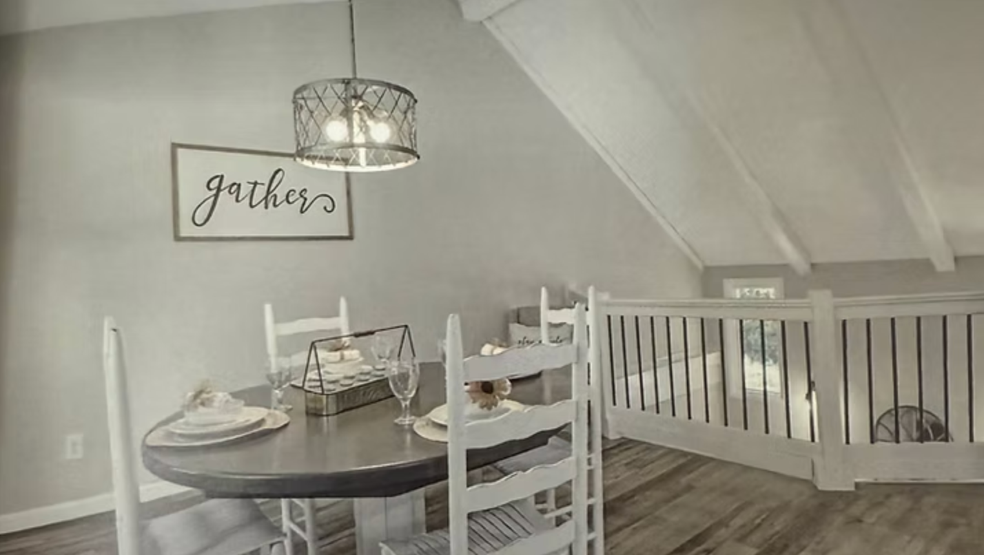 Dining room with round table set for a meal, four white chairs, light fixture, and a 