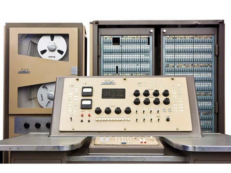 A vintage computer control panel with dials, switches, and tape drives. Beige and gray colors.