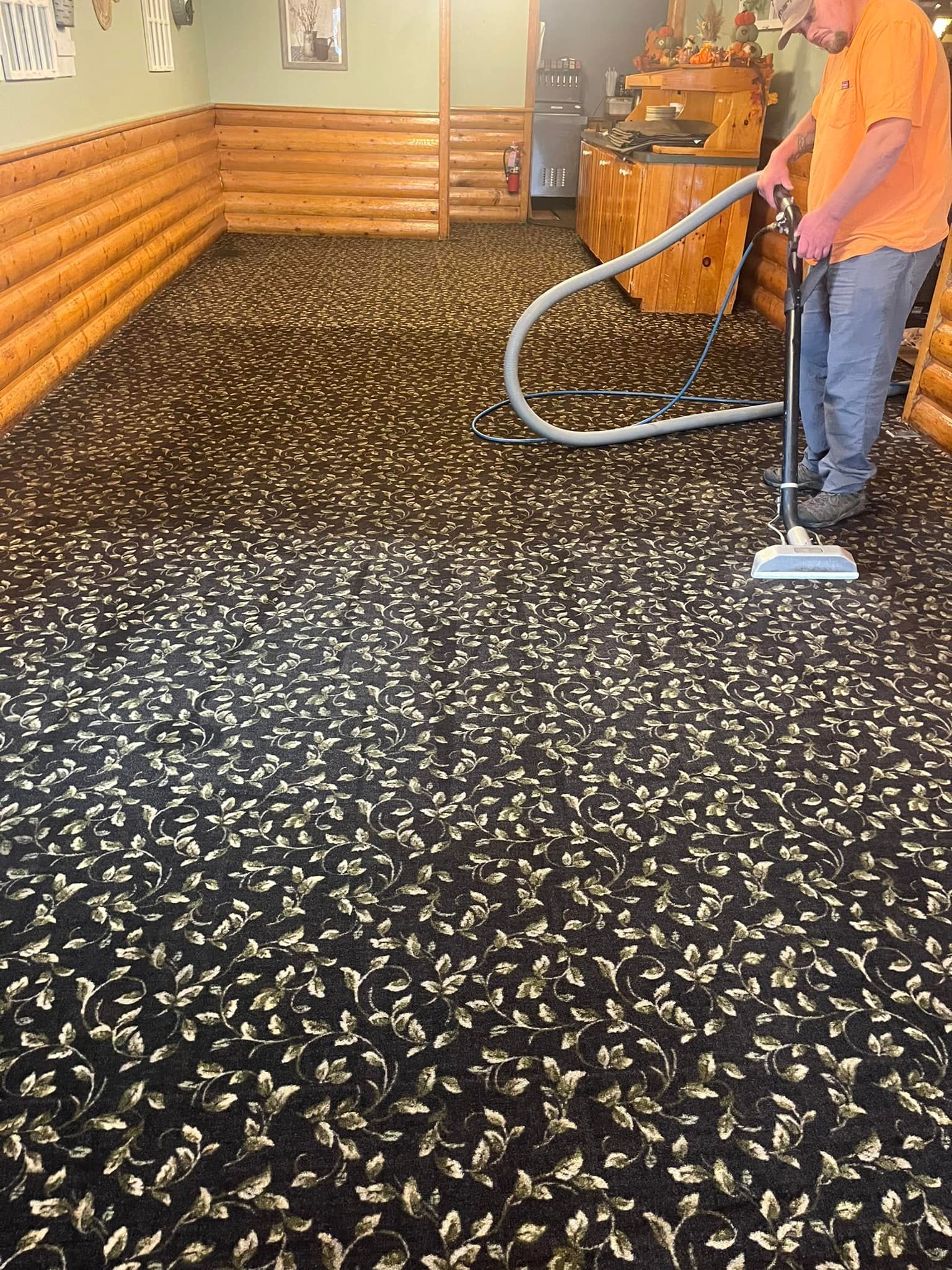 A man is using a vacuum cleaner to clean a carpet in a room.