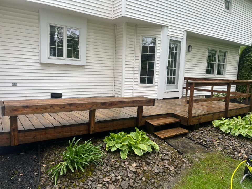 A white house with a wooden deck in front of it.