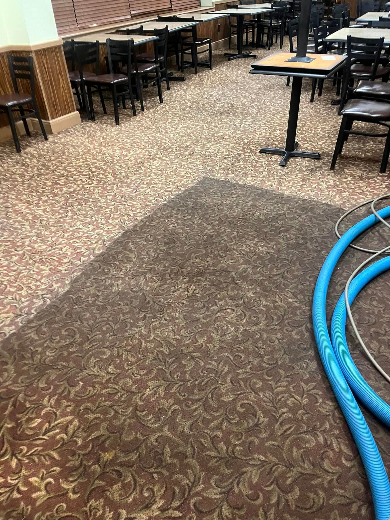 A restaurant with tables and chairs and a hose on the floor.