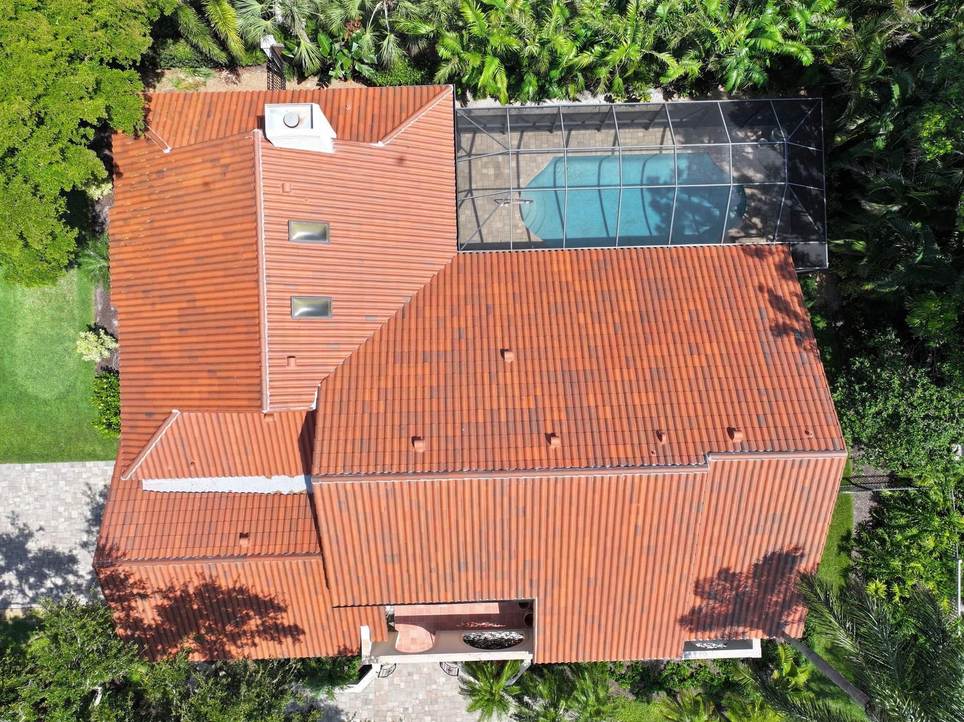 An aerial view of a house with a red tiled roof and a pool.