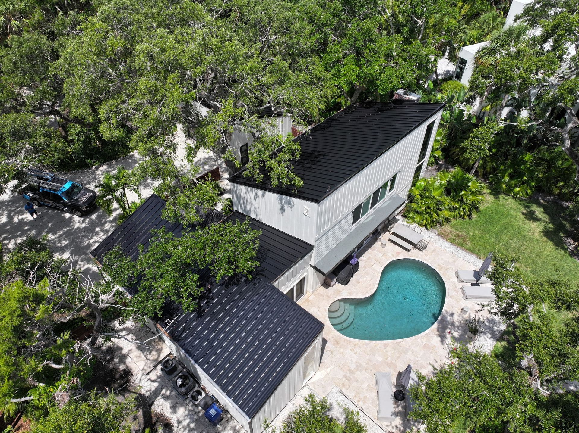 An aerial view of a house with a pool in the backyard surrounded by trees.