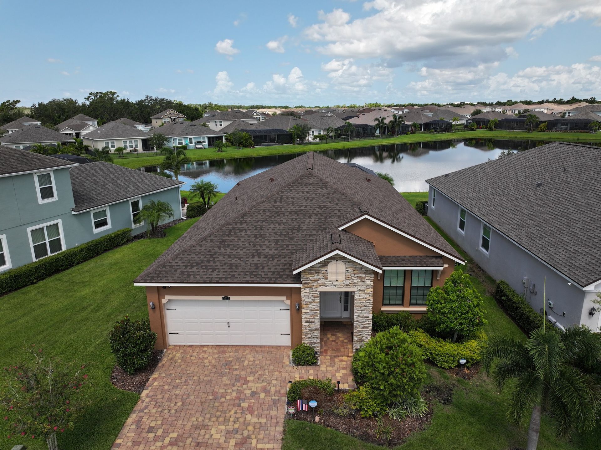 An aerial view of a house in a residential area with a lake in the background.