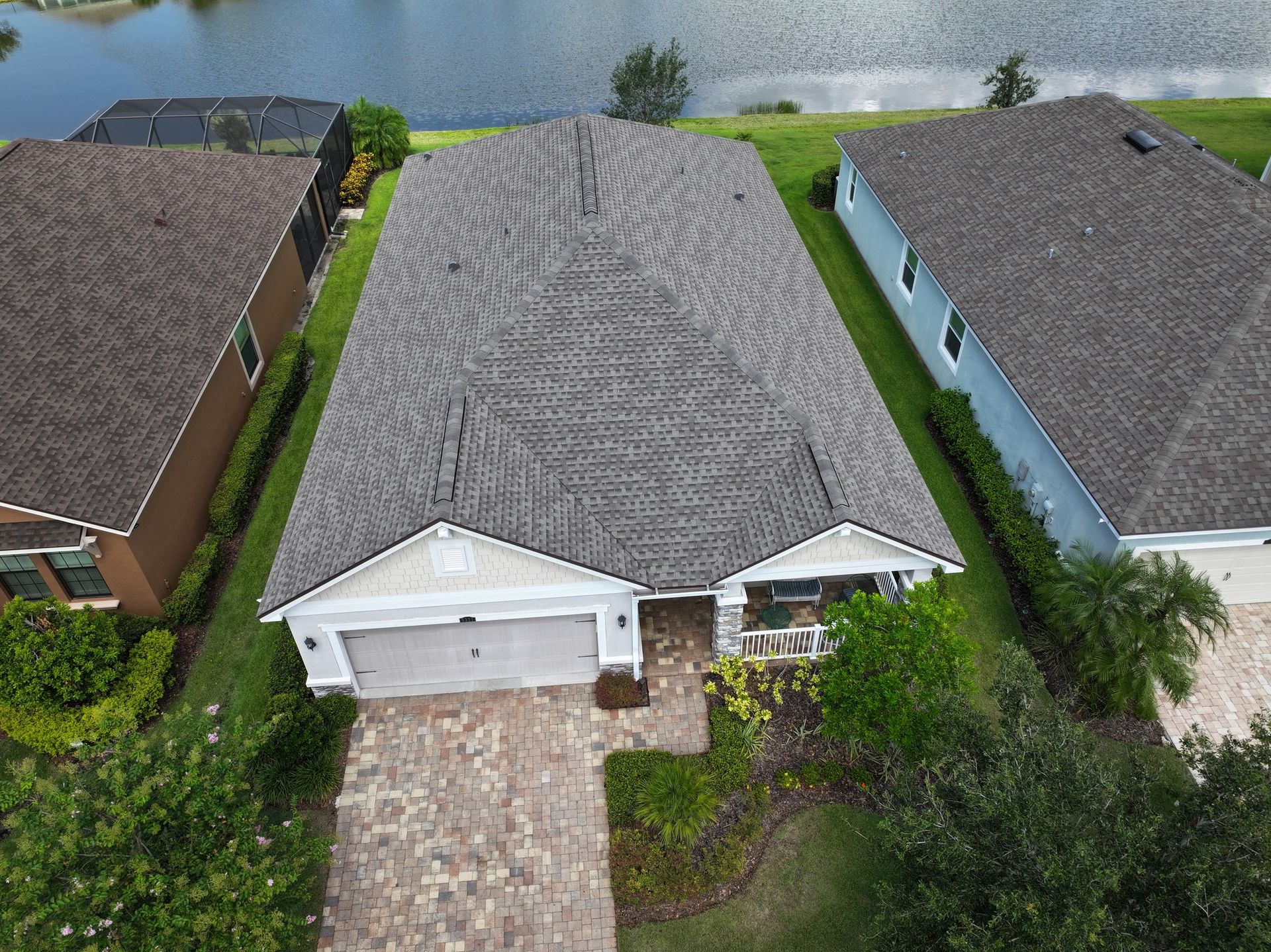 An aerial view of a house with a new roof and a lake in the background.