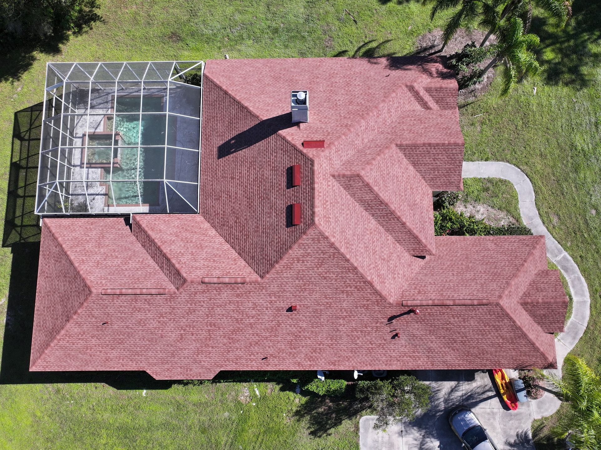 An aerial view of a house with a red roof and a pool.