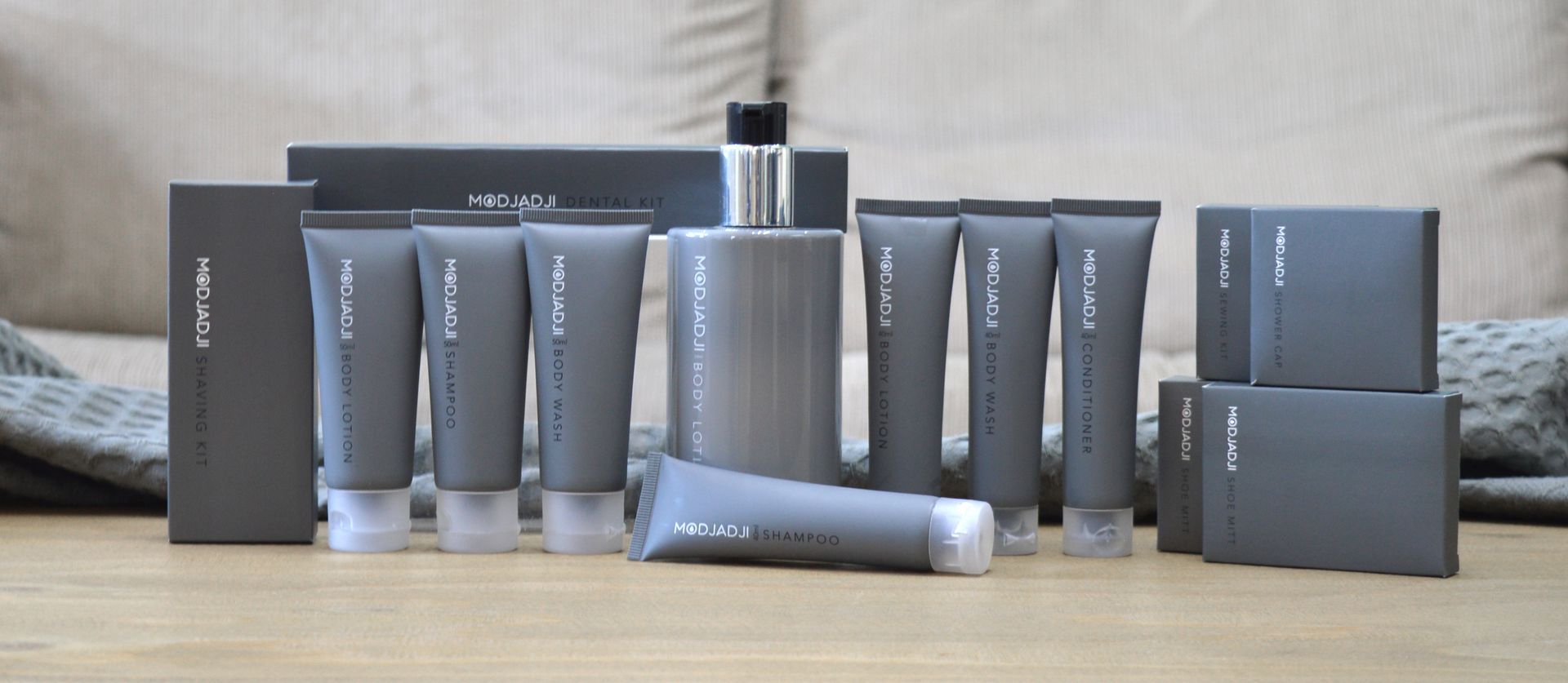 A row of gray bottles and boxes are lined up on a wooden table.