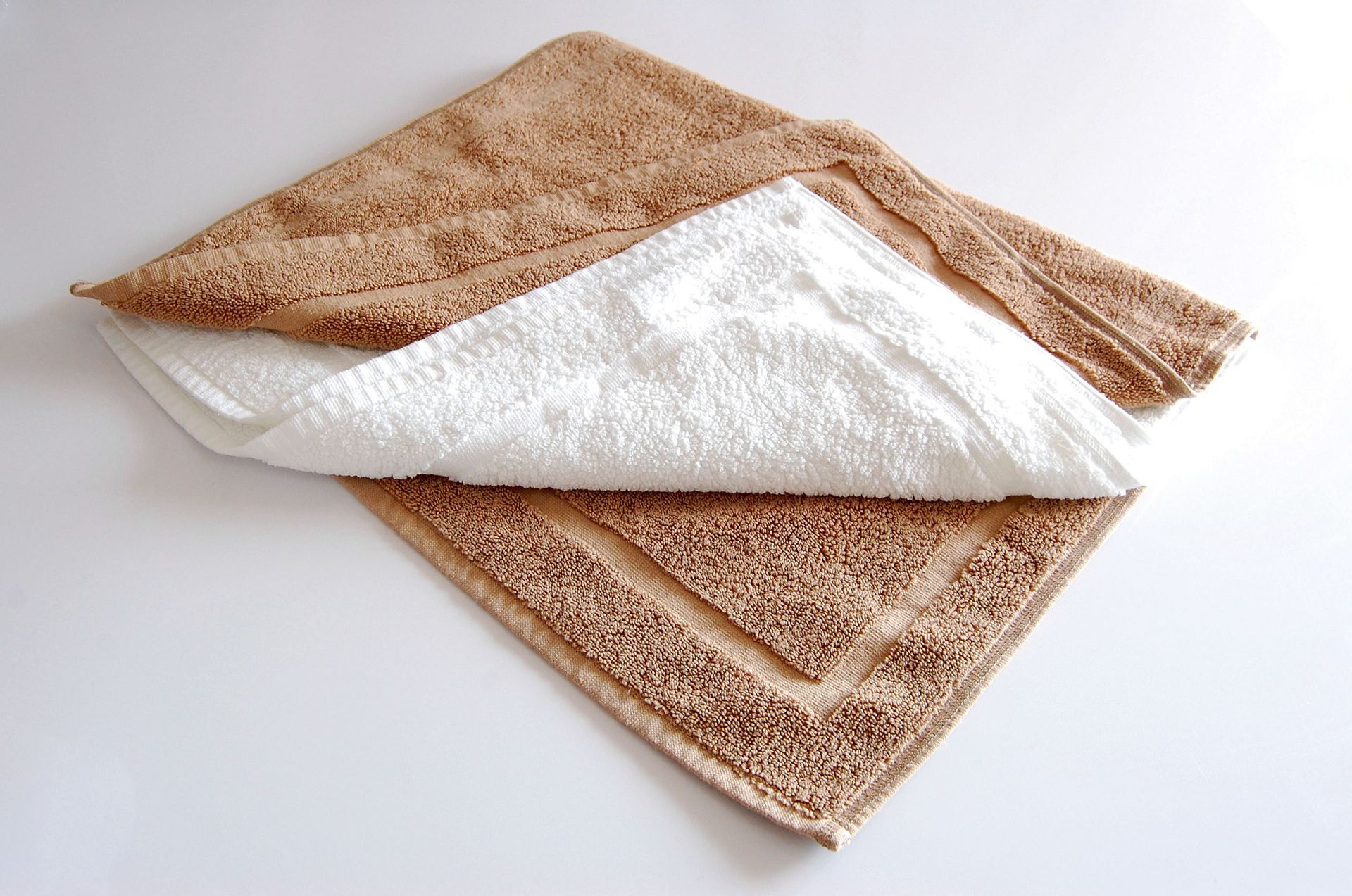 A brown and white towel folded in half on a white surface