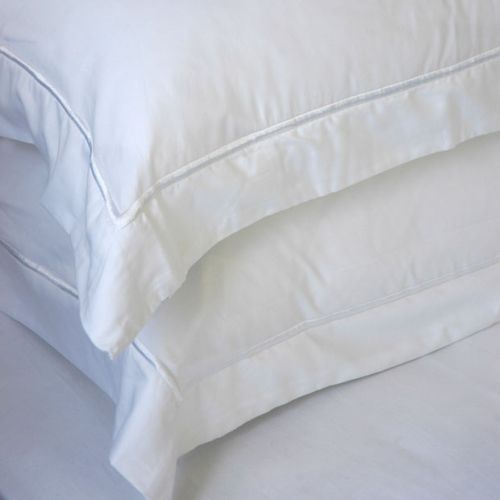 A stack of white pillows sitting on top of each other on a bed.