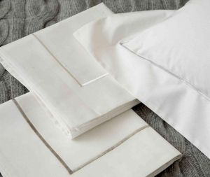 A stack of white sheets and pillows on a bed.