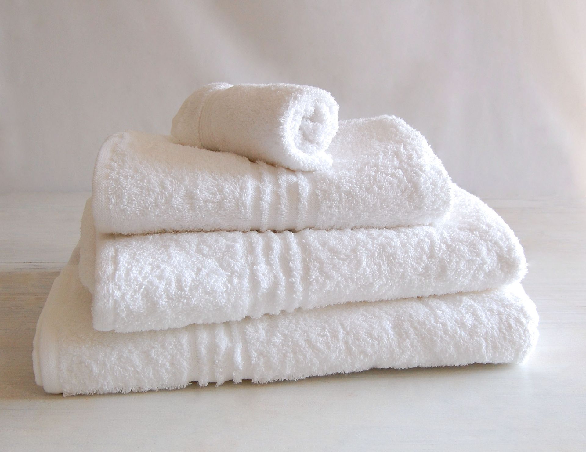 Four white towels are stacked on top of each other