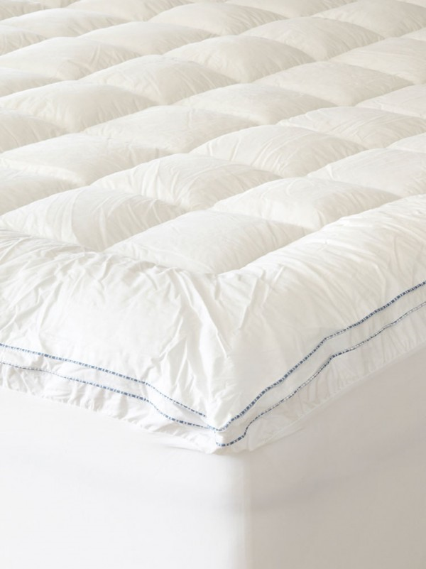 A close up of a white mattress topper on a bed.
