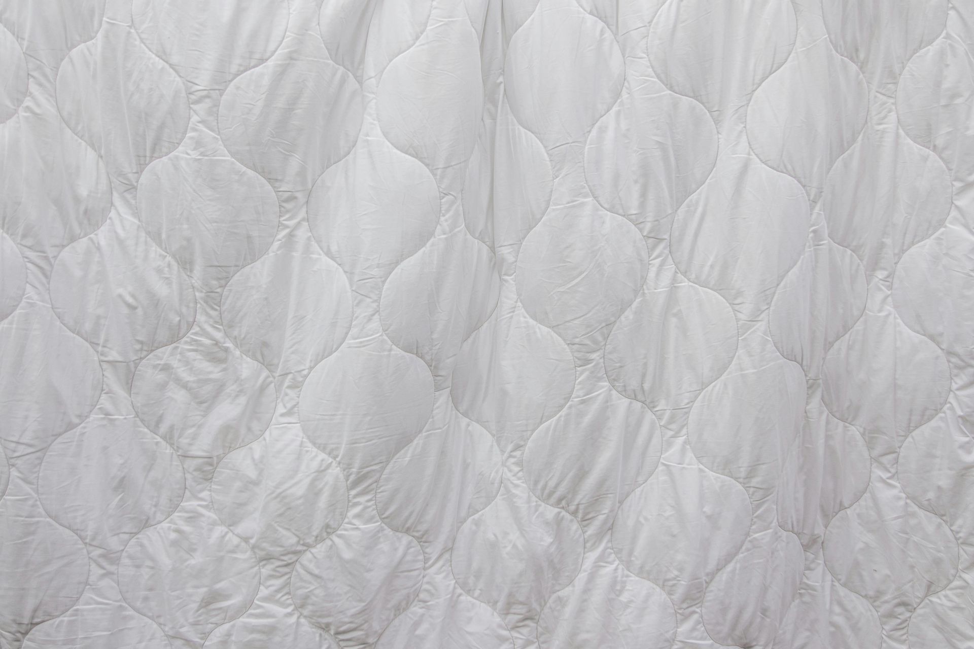 White quilted fabric with a repeating teardrop pattern.