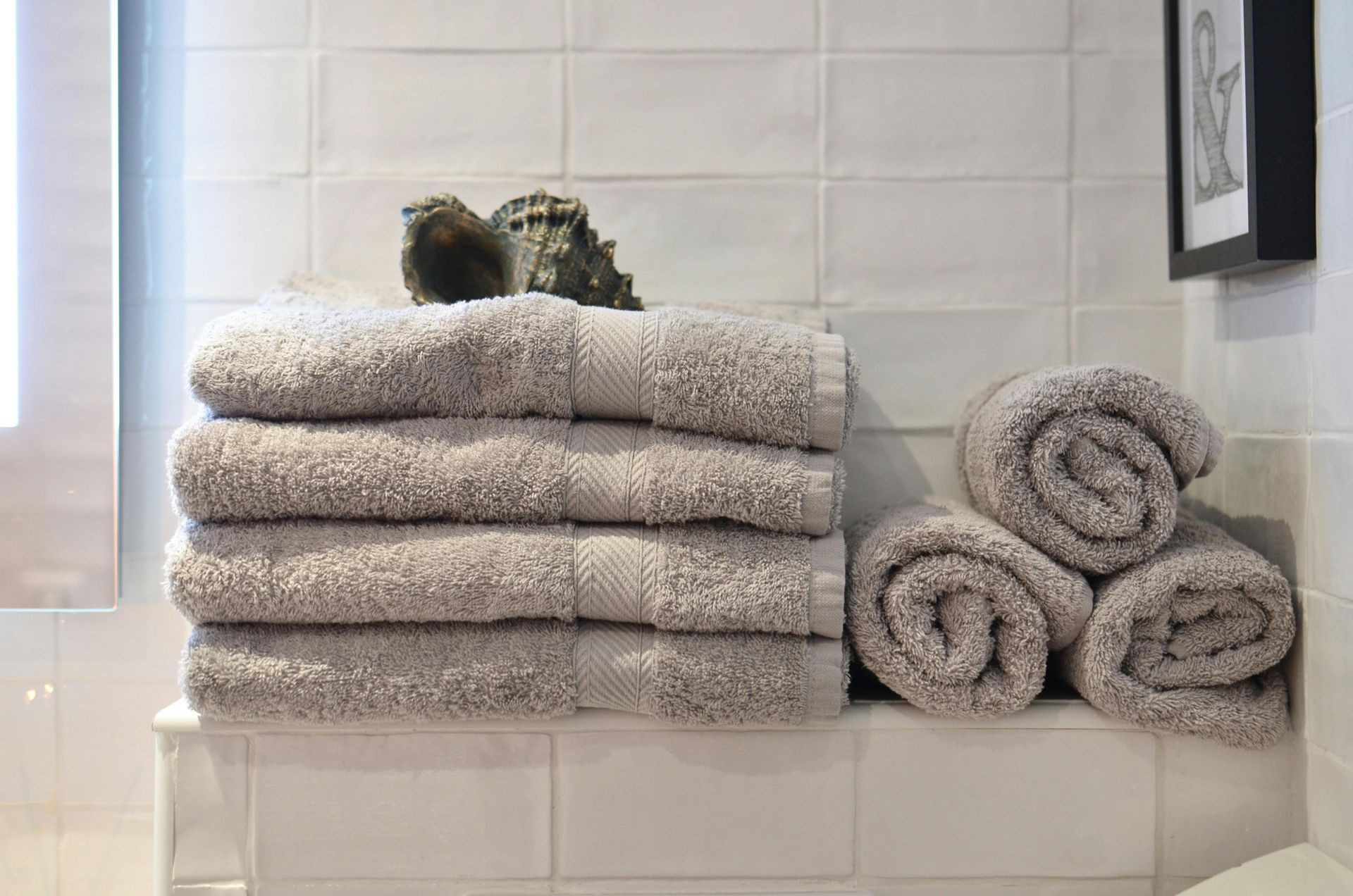A bathroom with a stack of towels and rolled up towels.