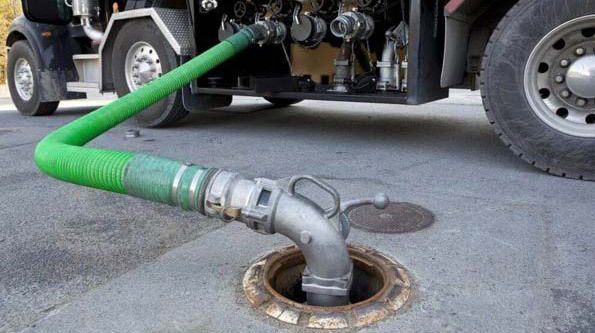 Green hose connected to fuel tank, attached to tanker truck.