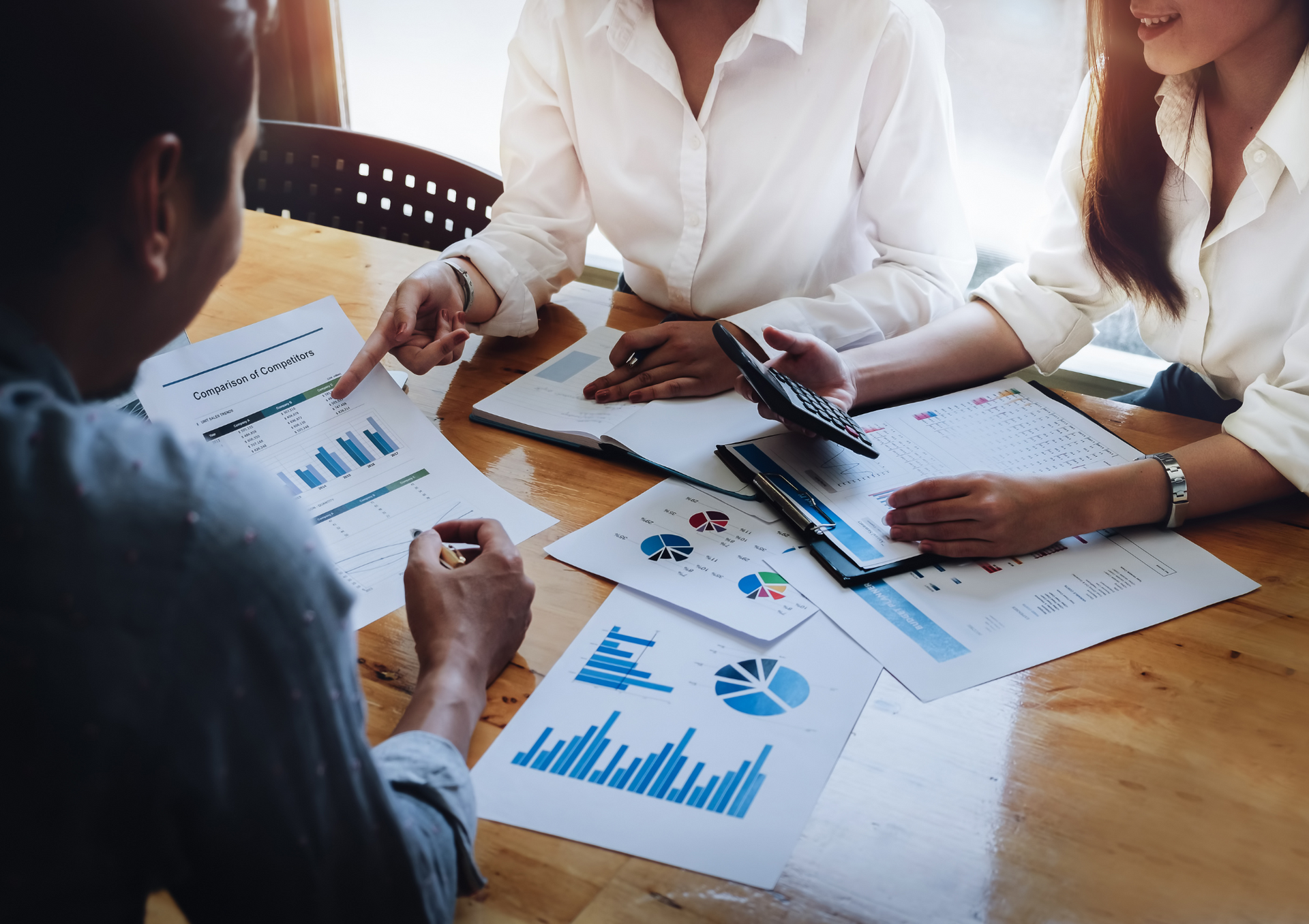 A group of people are sitting around a table looking at graphs.