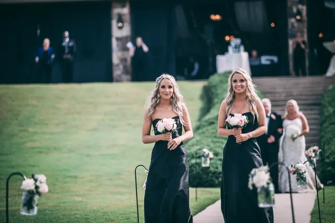 Two bridesmaids are walking down the aisle at a wedding.