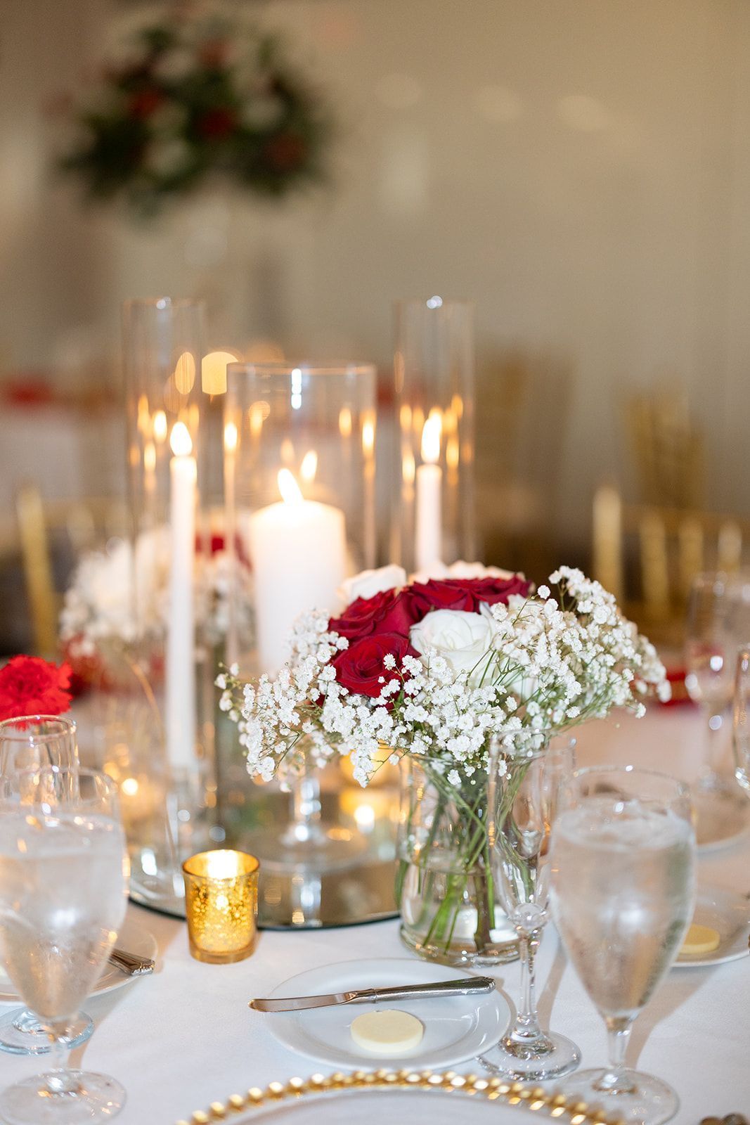 A table with a vase of flowers and candles on it.