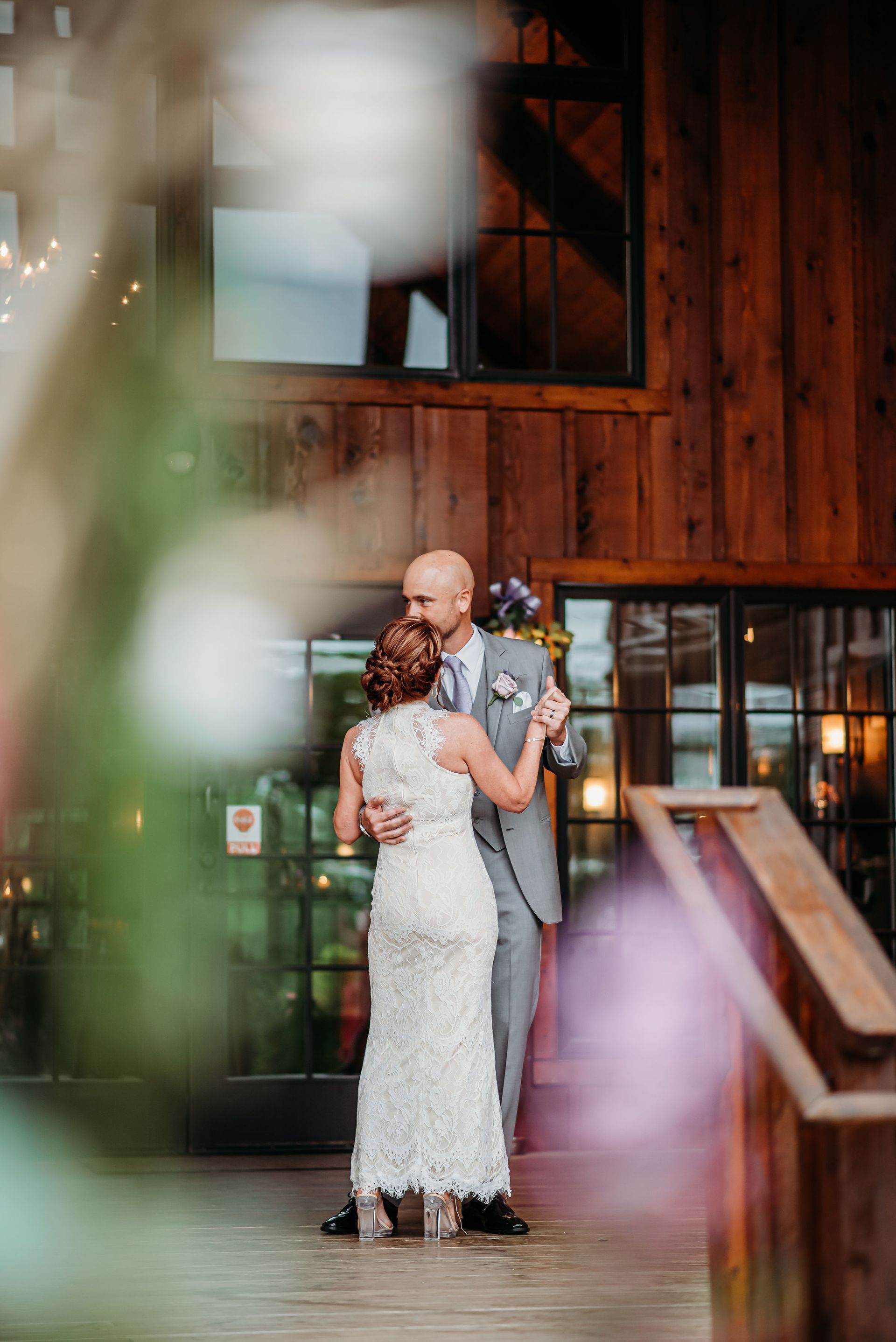 A bride and groom are dancing in front of a wooden building.