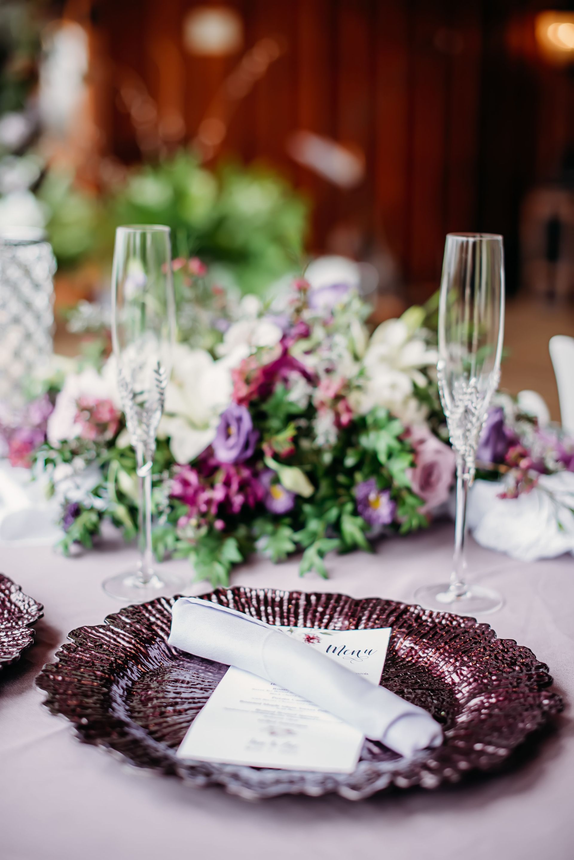 A table set for a wedding reception with plates , glasses , and flowers.