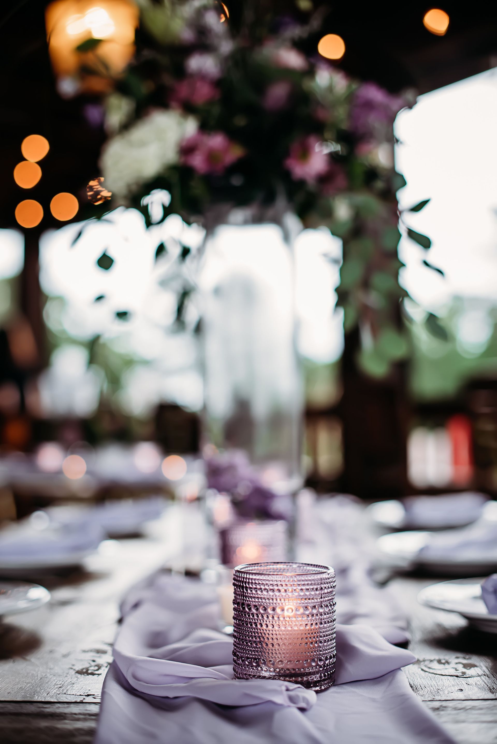 A candle is sitting on a table next to a vase of flowers.