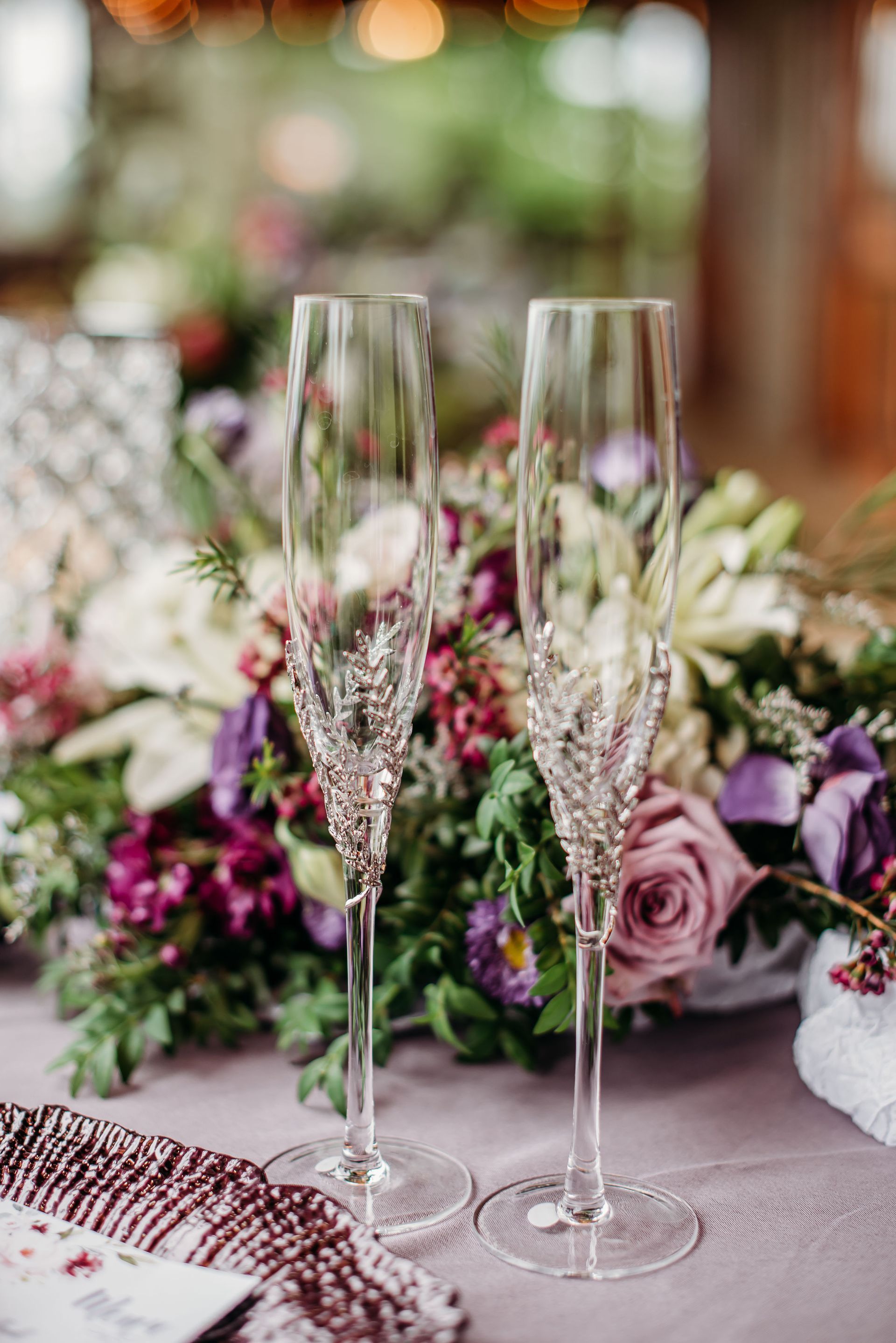 Two champagne flutes are sitting on a table with flowers in the background.