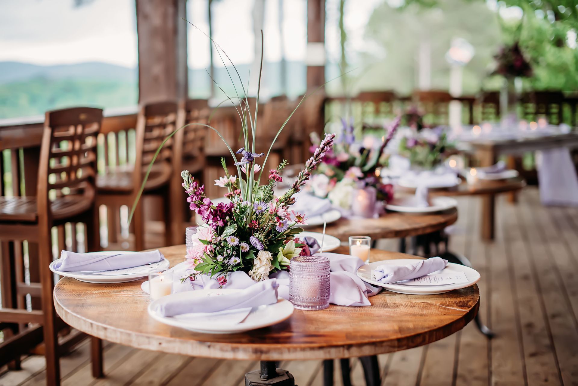 A wooden table with plates , napkins , and flowers on it.