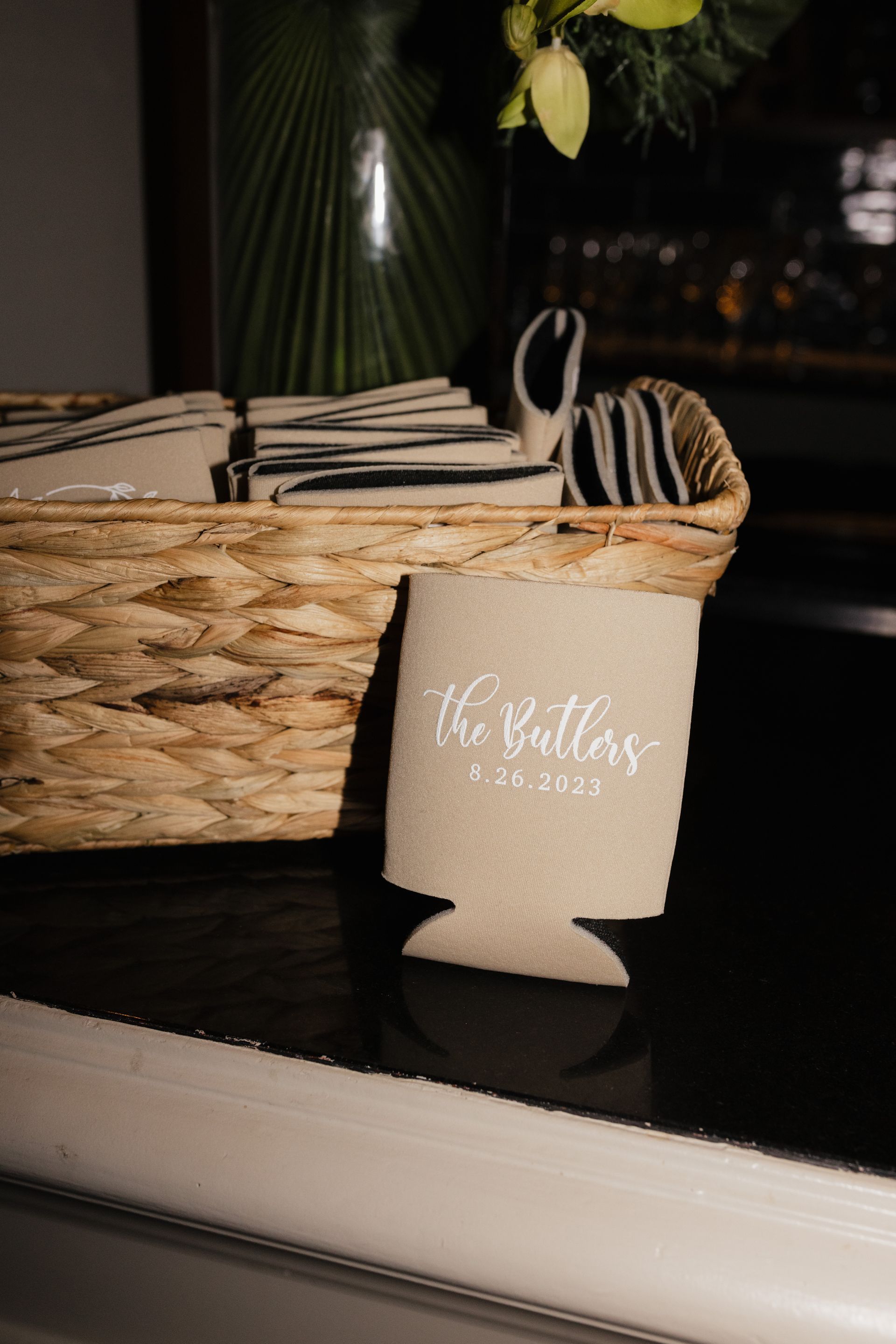 A can cooler is sitting on a table next to a basket of napkins.