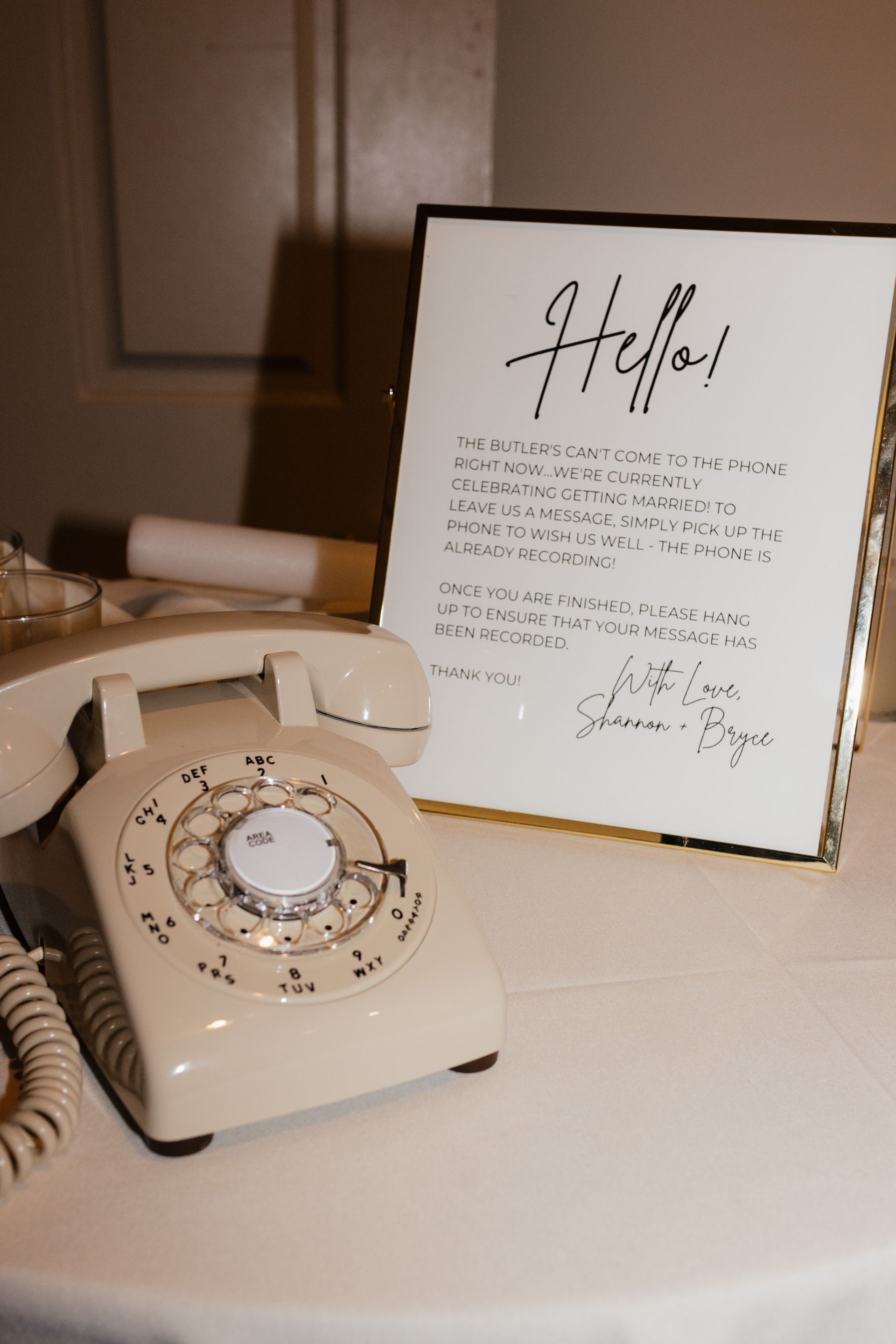 A white telephone is sitting on a table next to a sign that says hello.