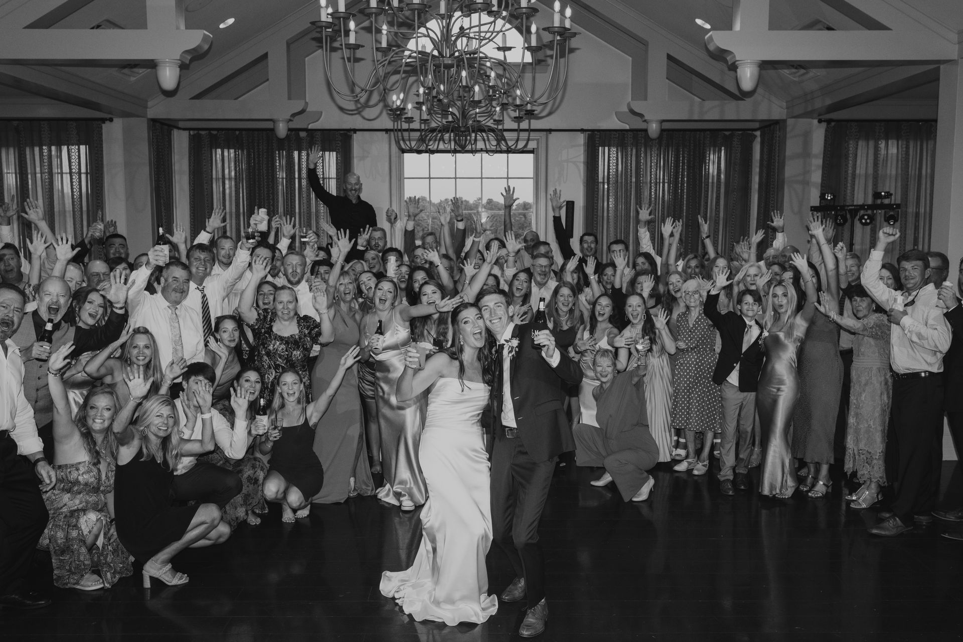 A large group of people are posing for a picture at a wedding reception.