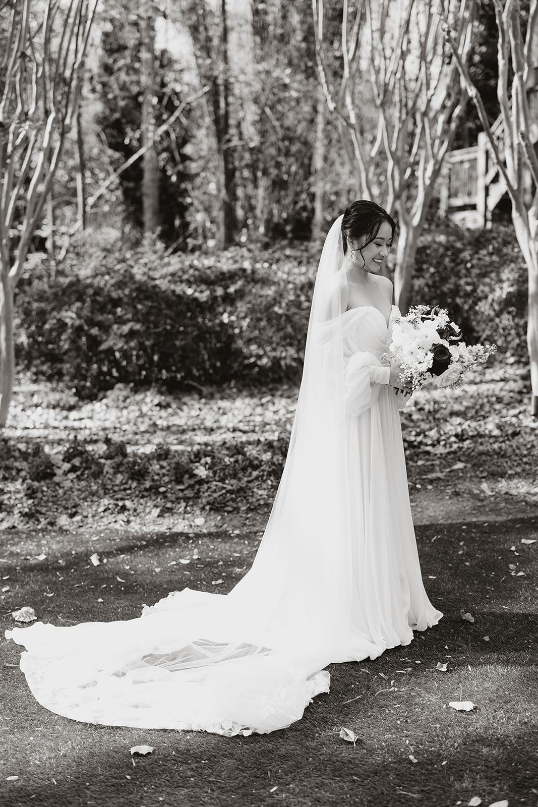 A black and white photo of a bride in a wedding dress holding a bouquet of flowers.