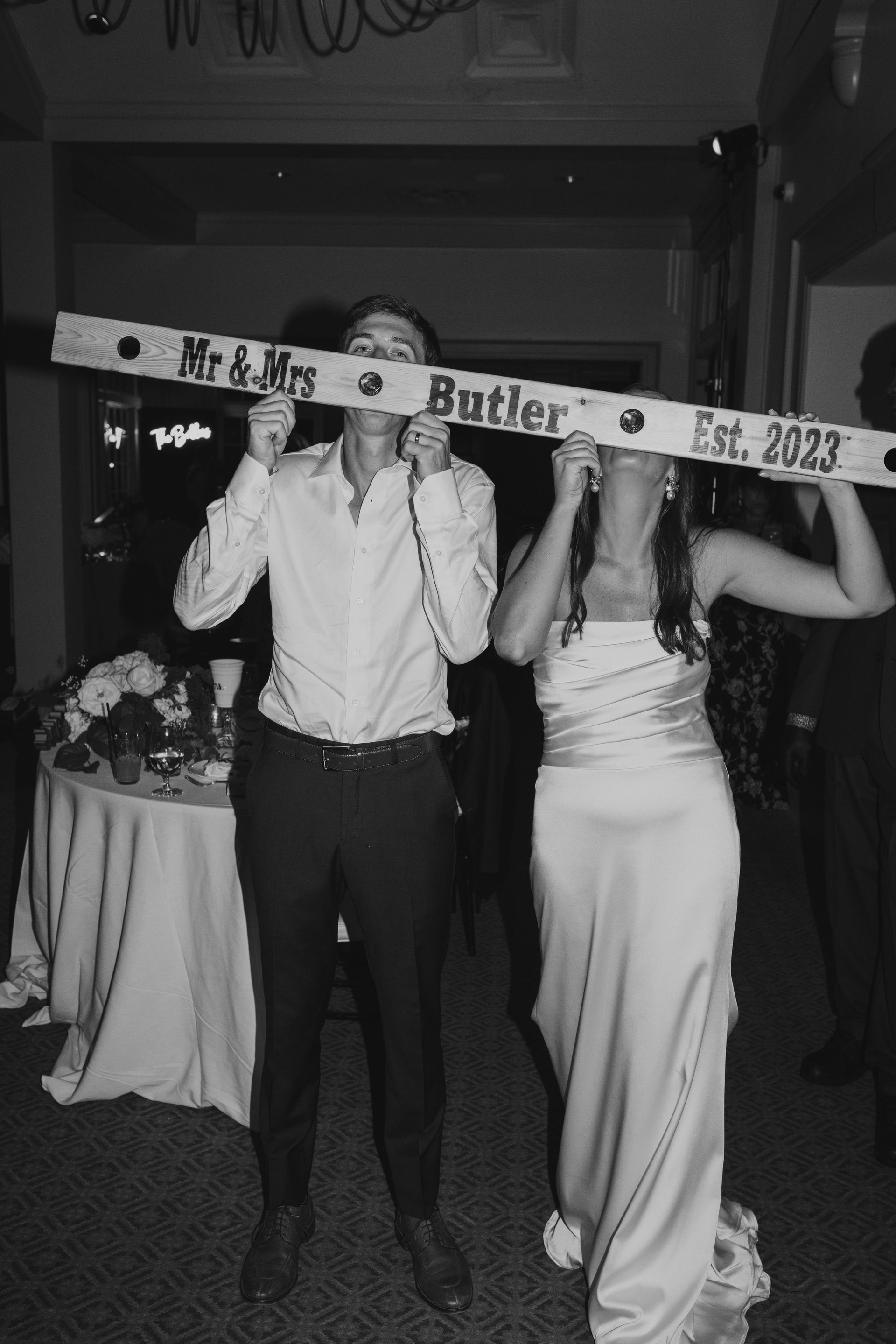 A bride and groom are holding a sign that says mr. and mrs. butler