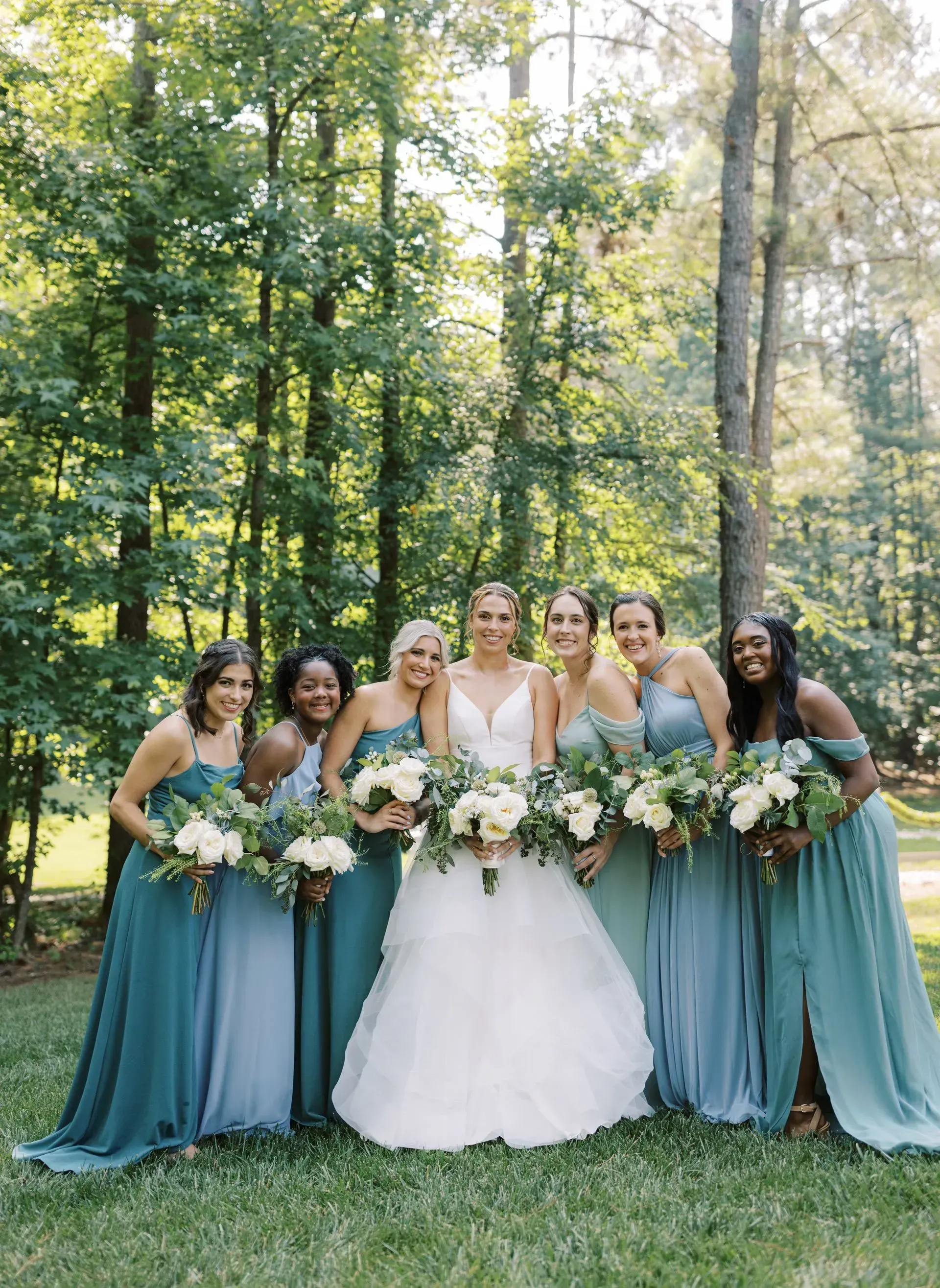 A bride and her bridesmaids are posing for a picture in the woods.