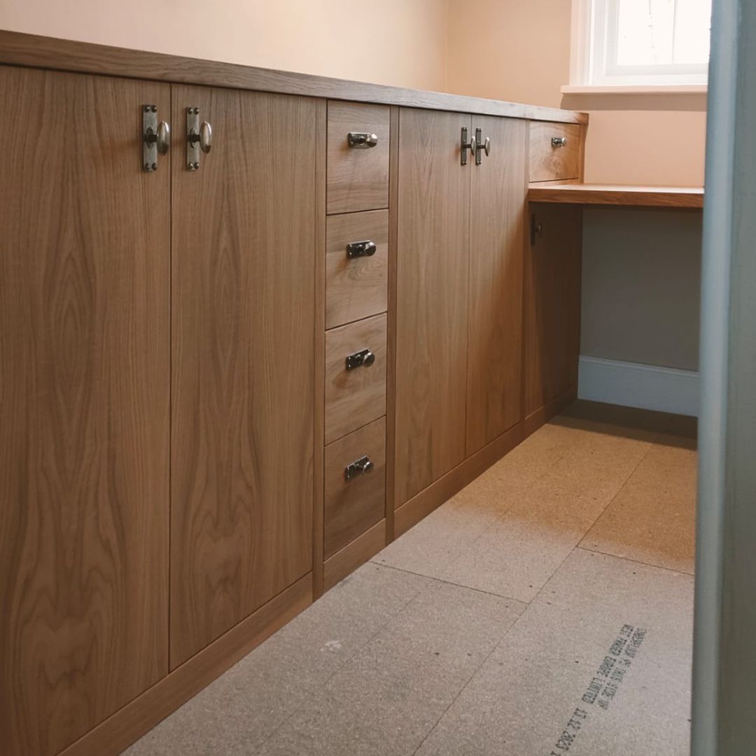 Custom wood cabinetry with double doors, a stack of four drawers, and a built-in desk surface along a wall.