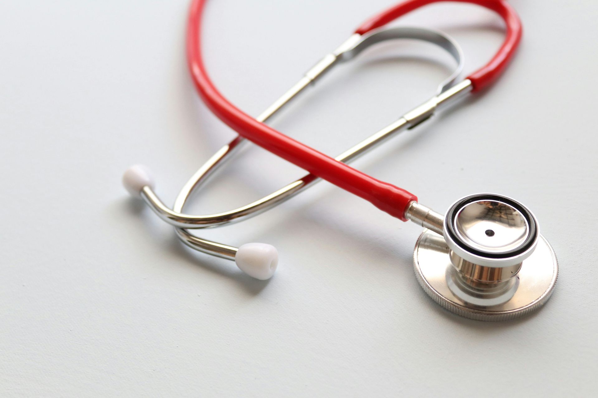 A red-tubed stethoscope rests against a plain white background.