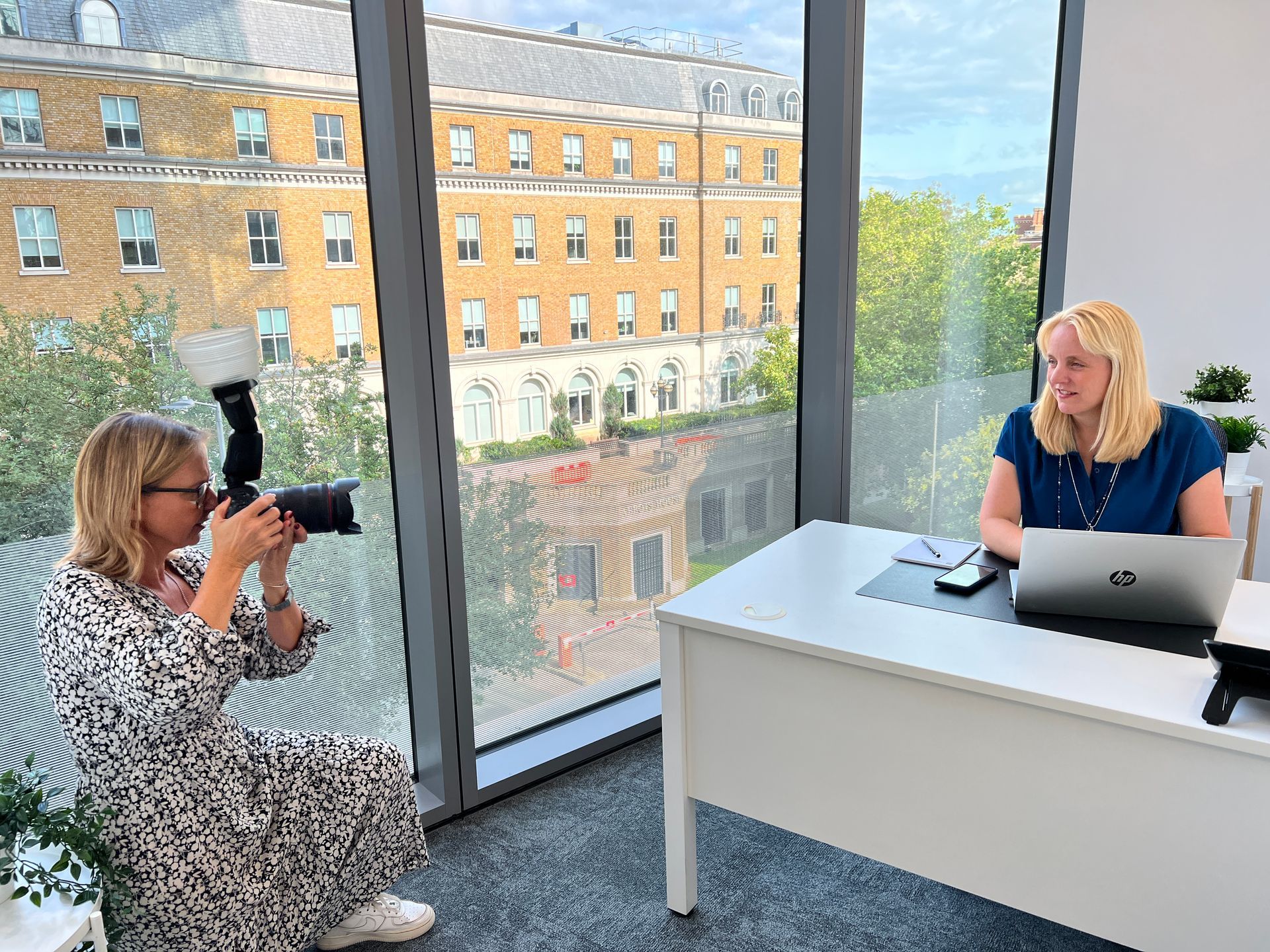 Commercial photographer reading, taking photo of female in glass office