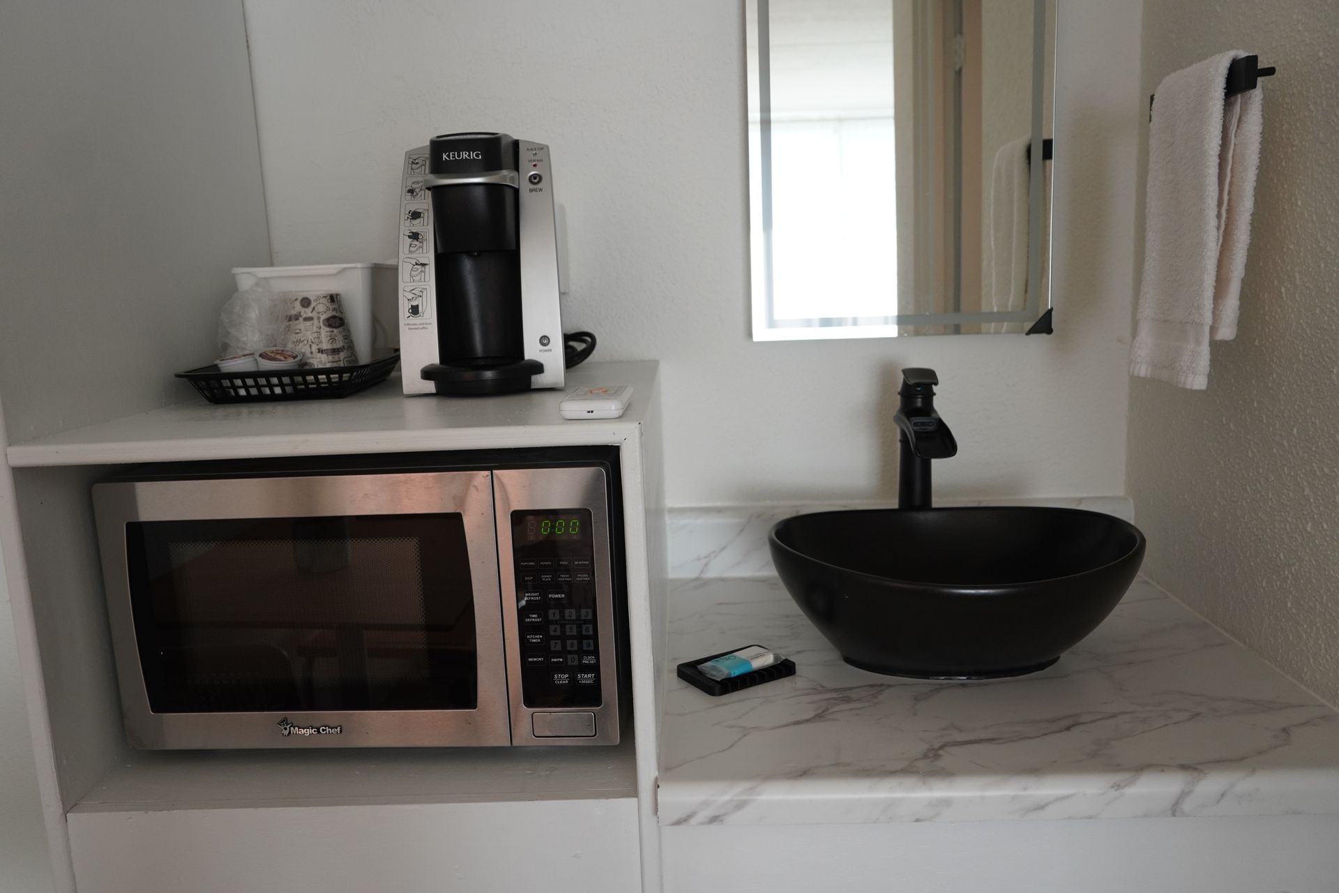A bathroom with a sink , microwave and coffee maker