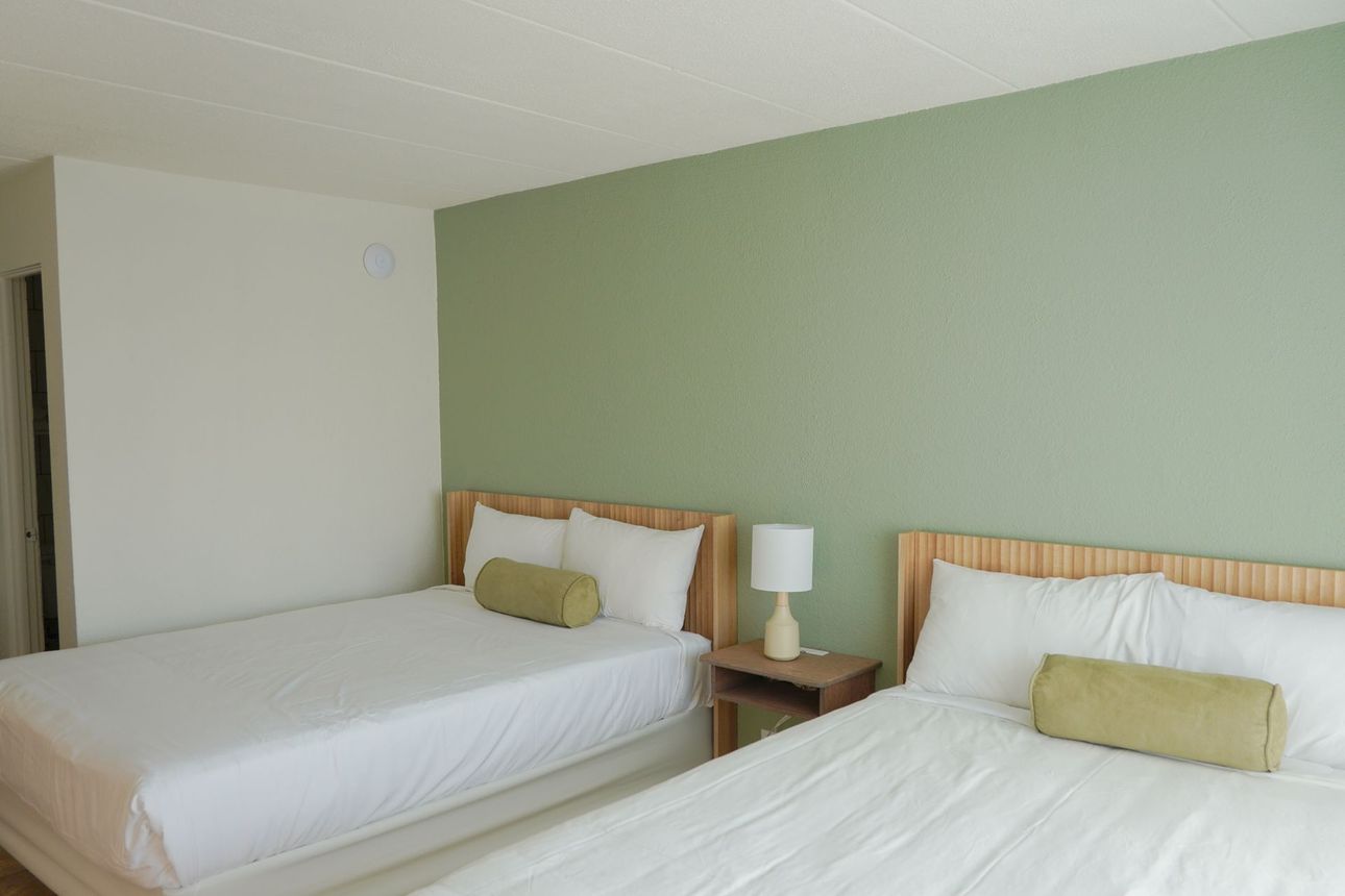 A hotel room with two beds , a microwave and a sink.