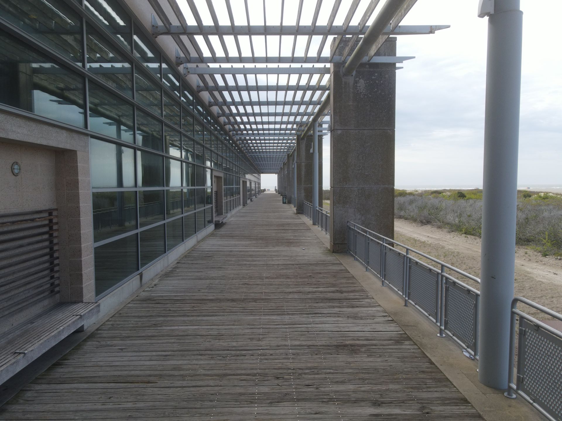 A long wooden walkway with a fence and a building in the background