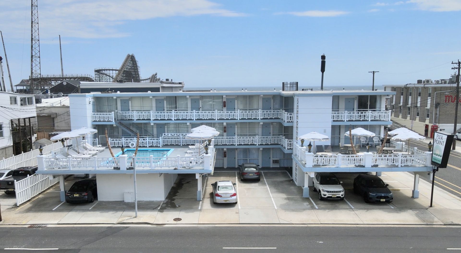 A large white building with a pool and cars parked in front of it.