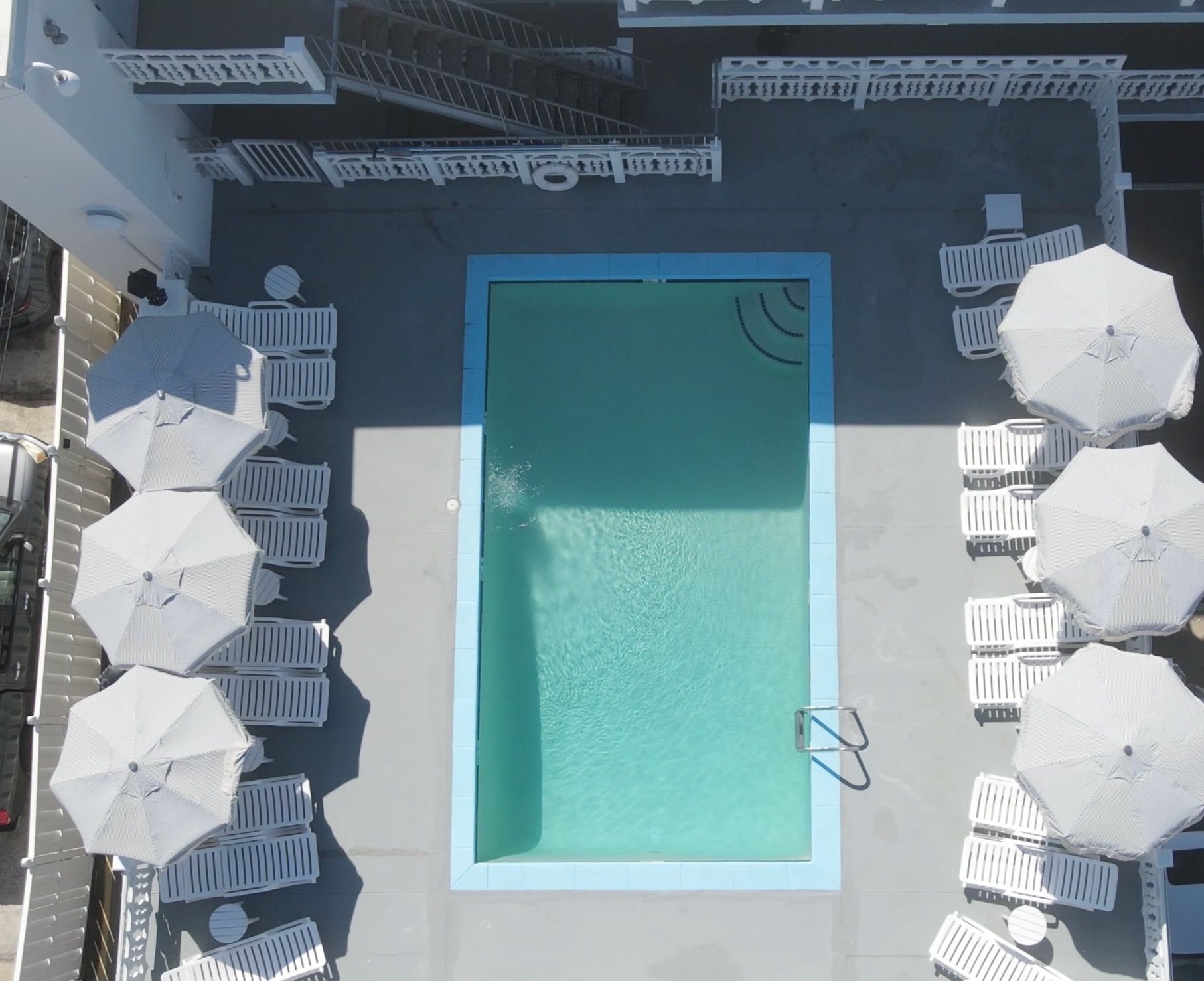 An aerial view of a swimming pool surrounded by chairs and umbrellas