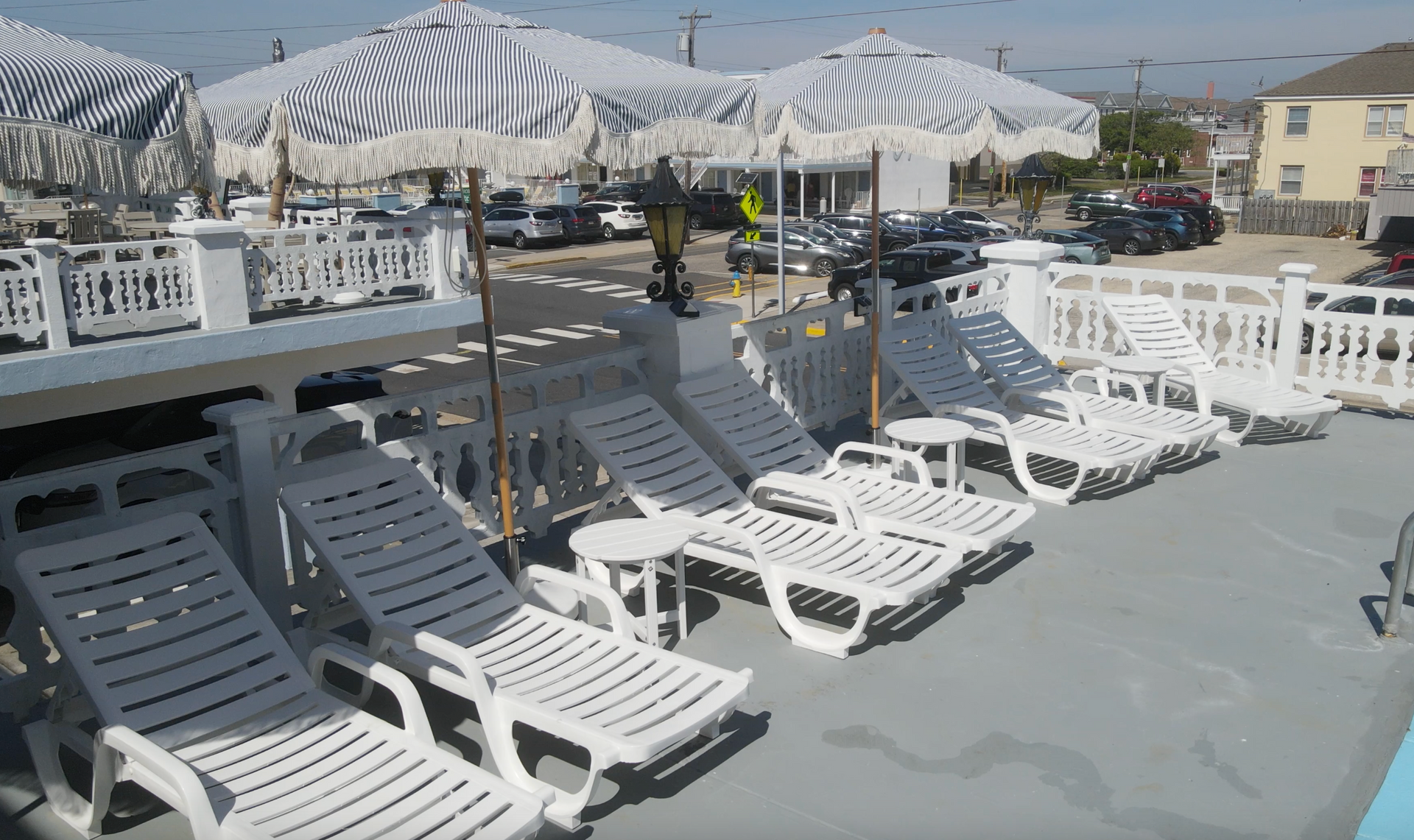 A row of white lounge chairs and umbrellas on a deck.