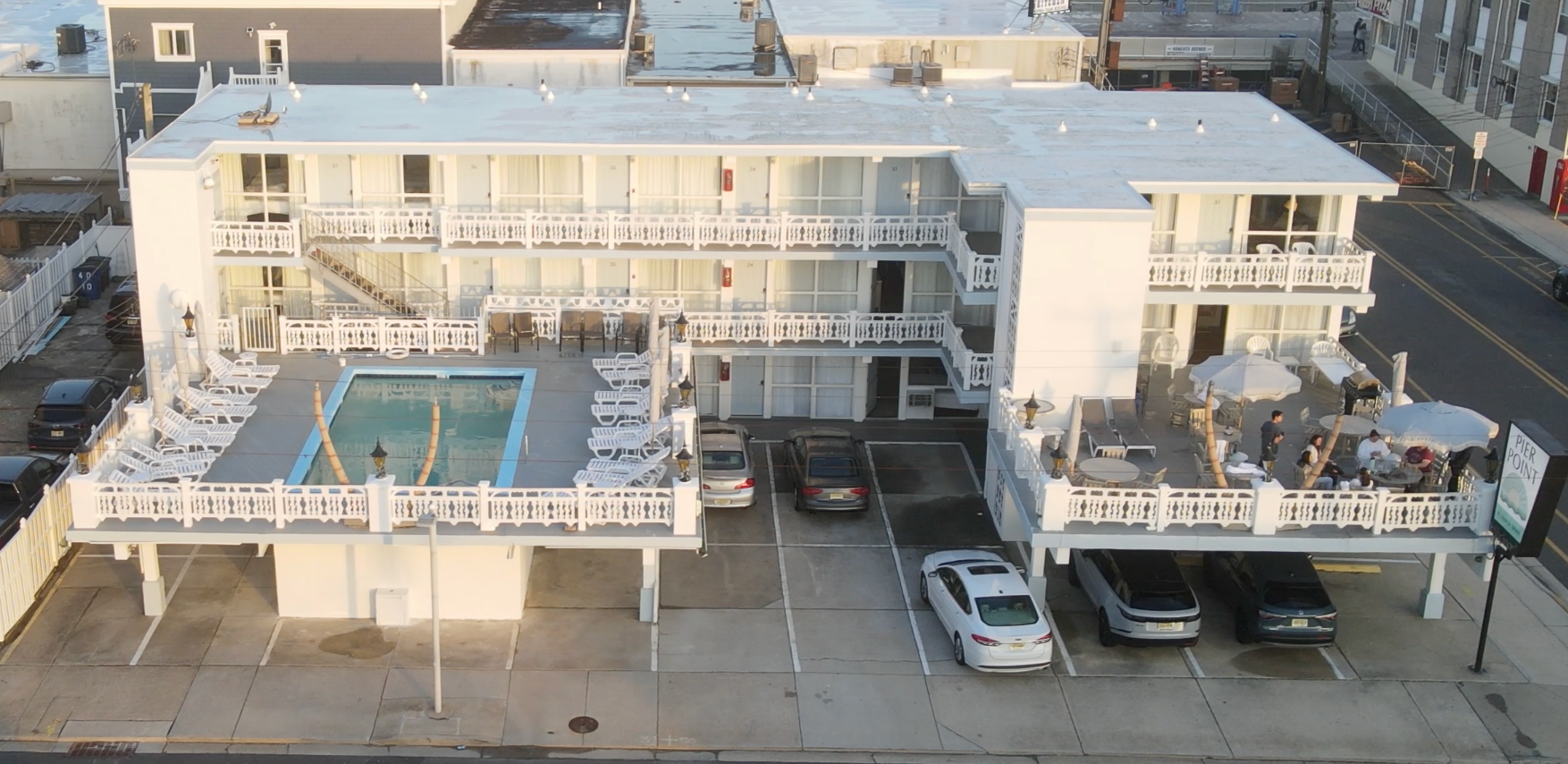 An aerial view of a hotel with a pool and cars parked in front of it