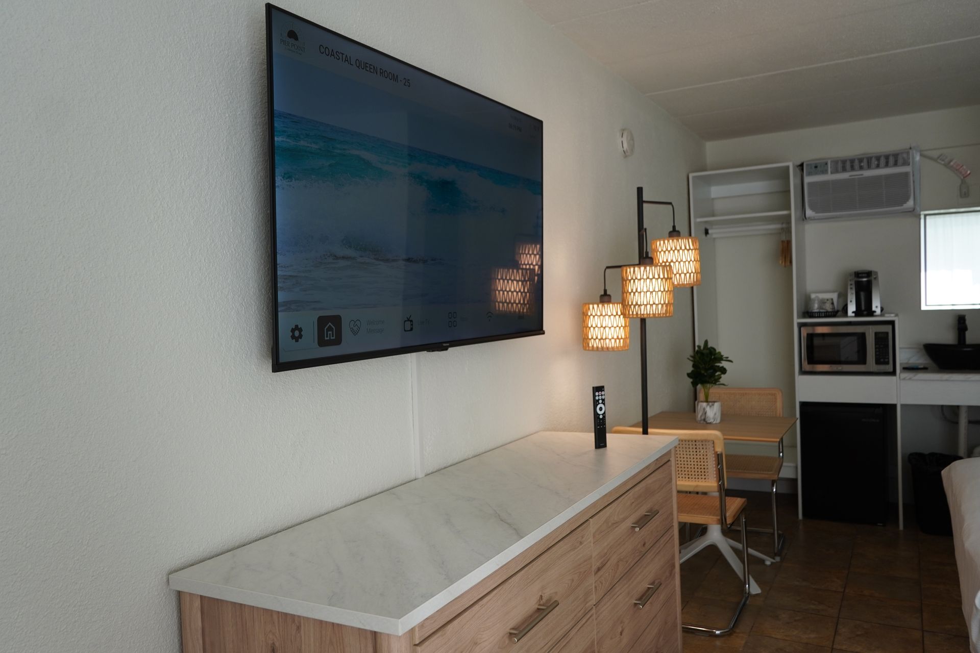 A flat screen tv is mounted on the wall above a dresser.
